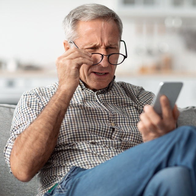 Poor,Eyesight.,Senior,Man,Squinting,Eyes,Reading,Message,On,Phone